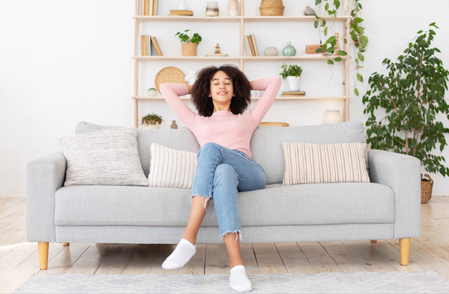 Young women relaxing on a couch, smiling with eyes closed after house was cleaned